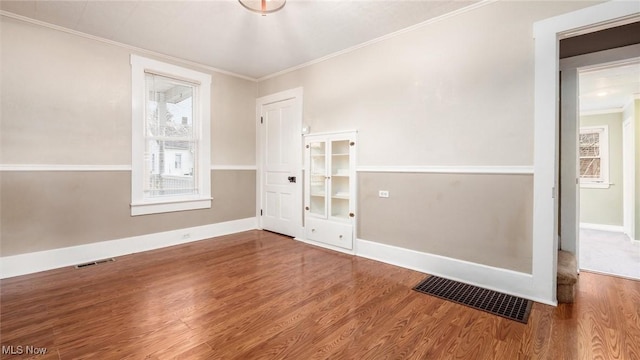 spare room with hardwood / wood-style flooring and crown molding