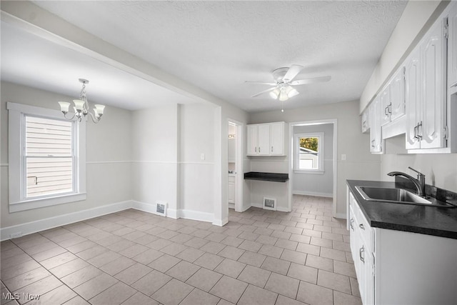 kitchen featuring a textured ceiling, ceiling fan with notable chandelier, white cabinetry, and sink