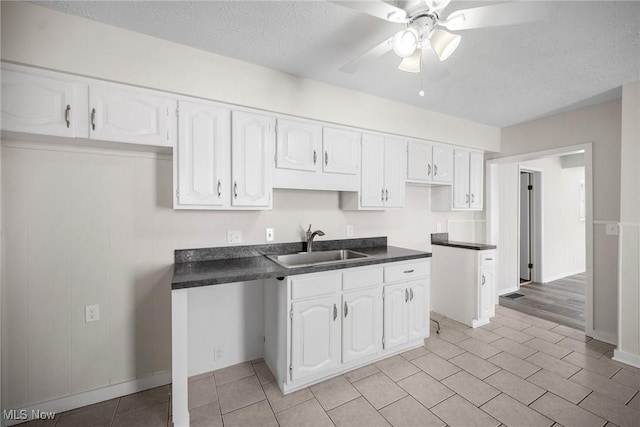 kitchen featuring white cabinets, ceiling fan, sink, and a textured ceiling