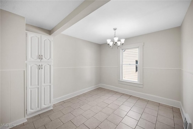 tiled spare room with a chandelier