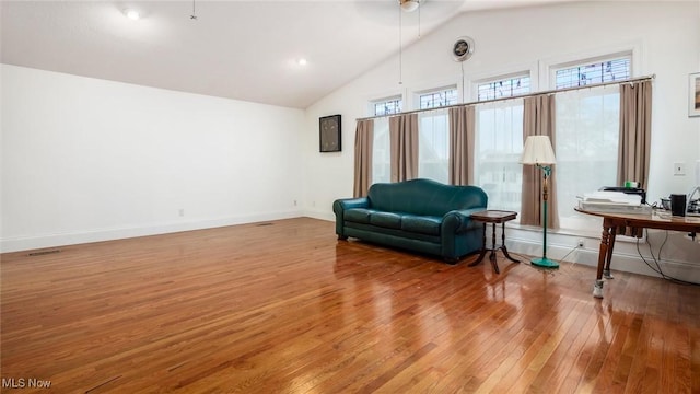 living area with high vaulted ceiling, ceiling fan, wood-type flooring, and a wealth of natural light