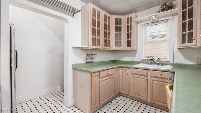 kitchen with light brown cabinets, light tile patterned flooring, and sink