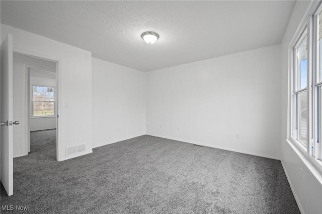 unfurnished room featuring a textured ceiling and dark carpet