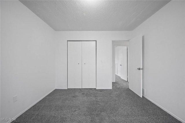 unfurnished bedroom featuring a closet, dark carpet, and a textured ceiling