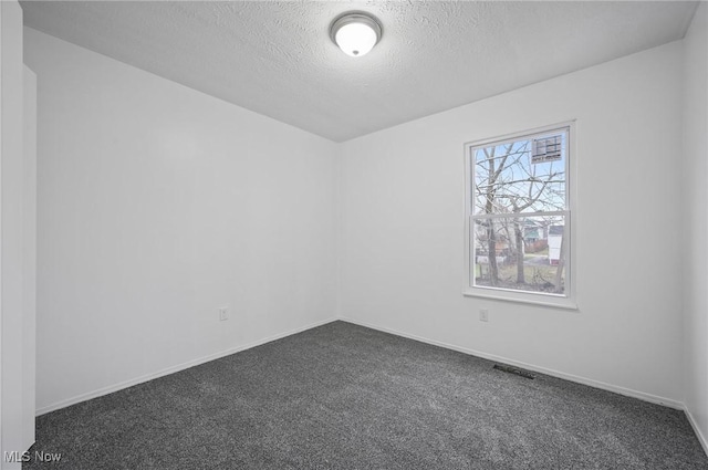 empty room featuring dark colored carpet and a textured ceiling