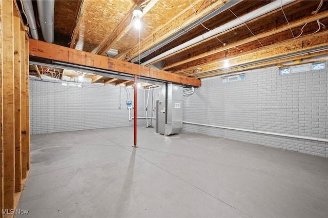 basement featuring heating unit and brick wall