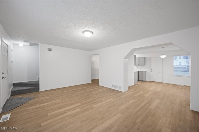 unfurnished living room with a textured ceiling and light wood-type flooring