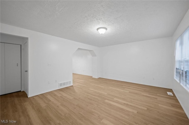 bonus room featuring light wood-type flooring and a textured ceiling