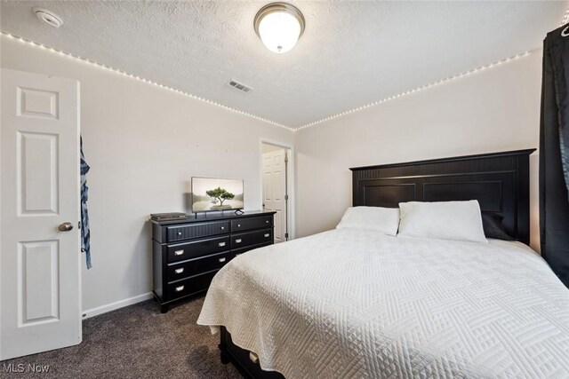 bedroom featuring visible vents, dark carpet, a textured ceiling, and baseboards