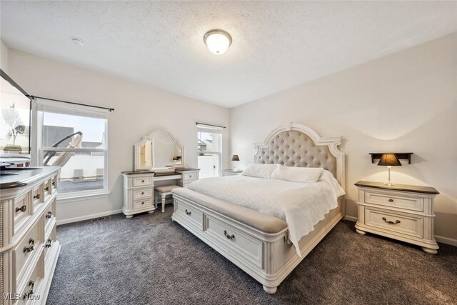 bedroom with baseboards, dark carpet, and a textured ceiling