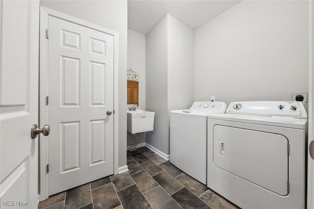 laundry room with a textured ceiling, laundry area, a sink, baseboards, and washer and dryer