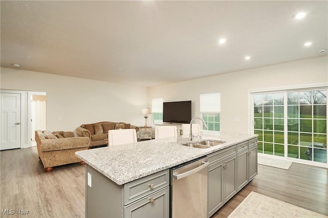 kitchen with dishwasher, an island with sink, light hardwood / wood-style floors, sink, and gray cabinets