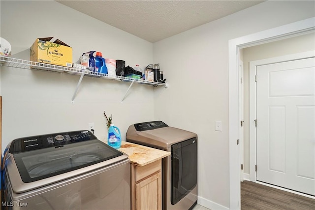 clothes washing area with a textured ceiling, separate washer and dryer, cabinets, and dark wood-type flooring