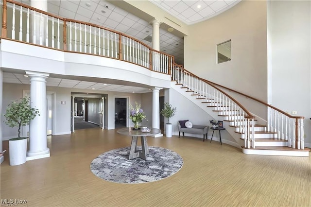 foyer featuring hardwood / wood-style flooring, a high ceiling, and decorative columns