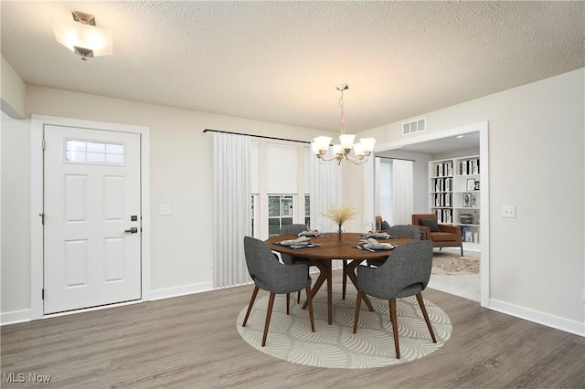 dining space featuring dark hardwood / wood-style flooring, an inviting chandelier, and a textured ceiling