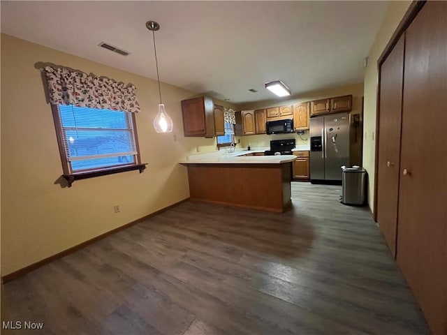 kitchen with pendant lighting, black appliances, sink, dark hardwood / wood-style floors, and kitchen peninsula