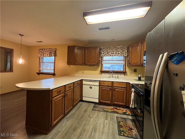 kitchen with kitchen peninsula, stainless steel fridge, white dishwasher, sink, and pendant lighting