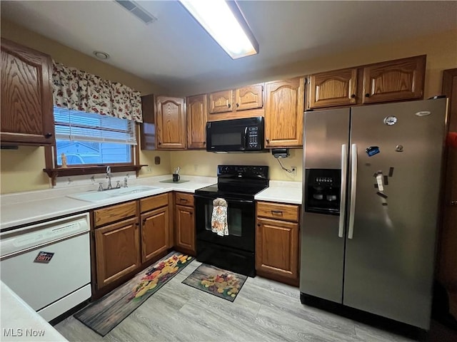 kitchen with sink, black appliances, and light hardwood / wood-style floors