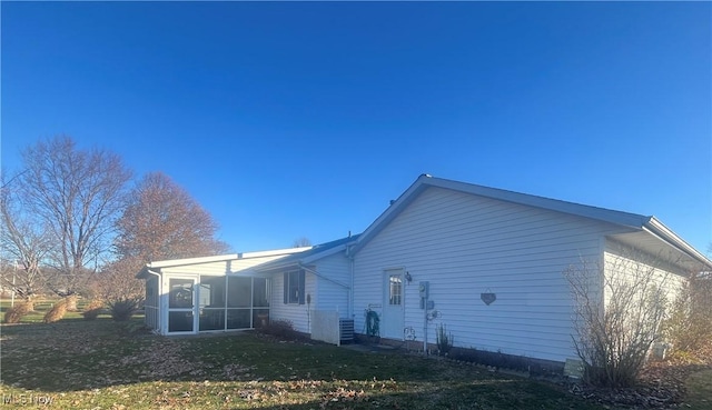 rear view of house featuring a lawn and a sunroom