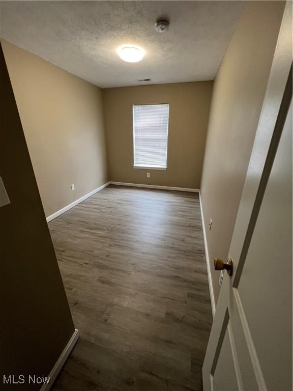 empty room featuring a textured ceiling and dark wood-type flooring