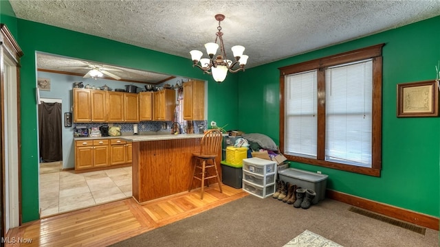 kitchen featuring pendant lighting, light wood-type flooring, kitchen peninsula, and a textured ceiling