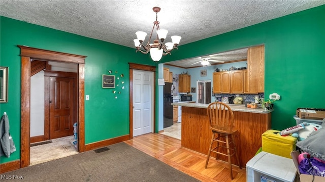 kitchen featuring pendant lighting, kitchen peninsula, a textured ceiling, and light hardwood / wood-style flooring