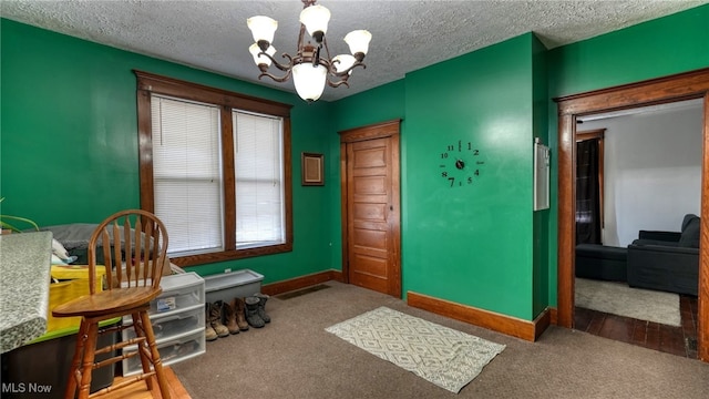 interior space featuring a textured ceiling, carpet floors, and an inviting chandelier