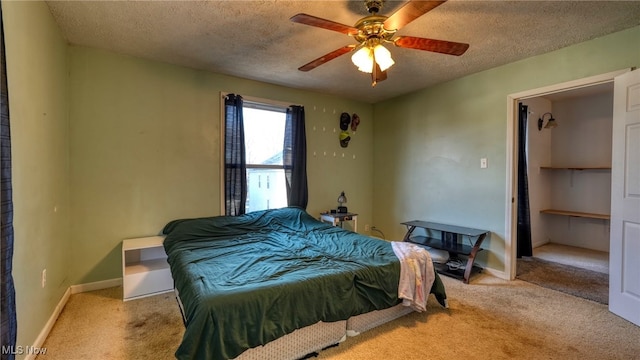 bedroom with ceiling fan, light colored carpet, and a textured ceiling