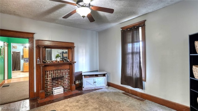 living room featuring ceiling fan, dark carpet, a textured ceiling, and a fireplace