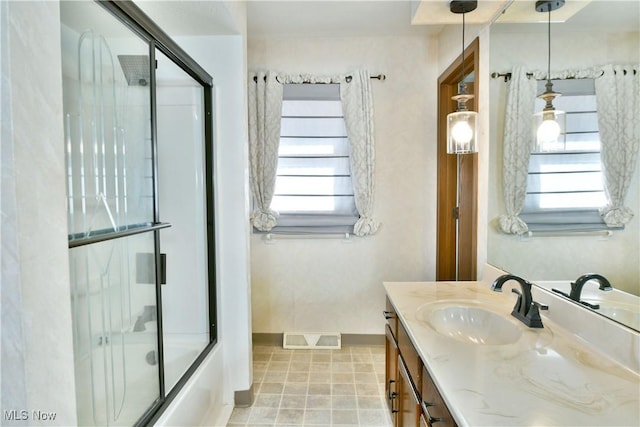 bathroom with vanity, a healthy amount of sunlight, and combined bath / shower with glass door