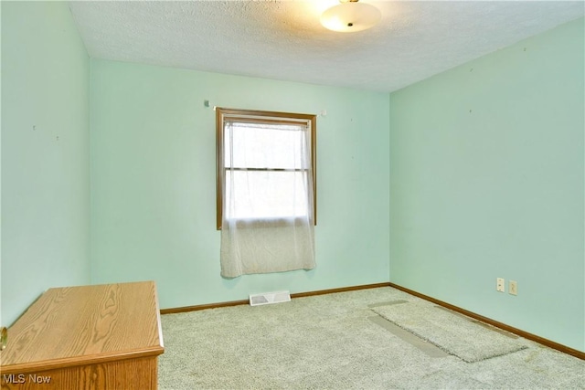 carpeted empty room with a textured ceiling