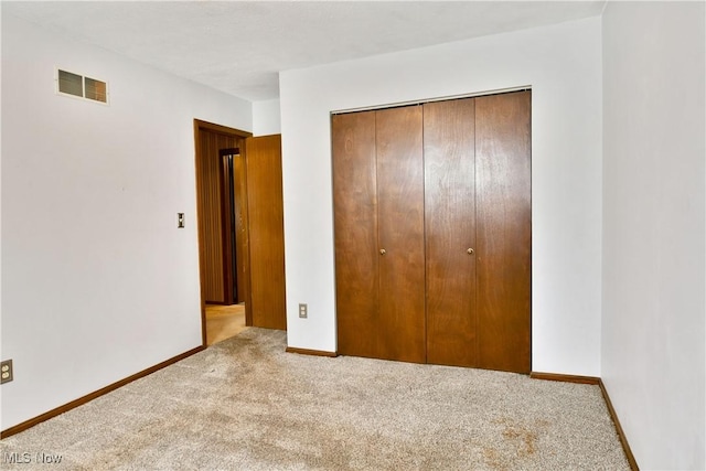 unfurnished bedroom with light carpet and a closet