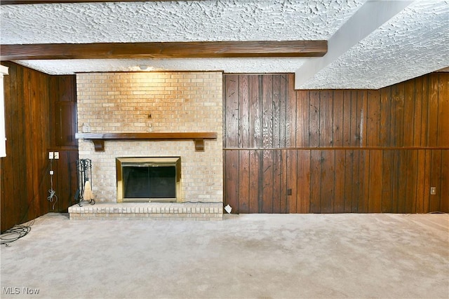 unfurnished living room featuring carpet flooring, beam ceiling, a fireplace, and wooden walls