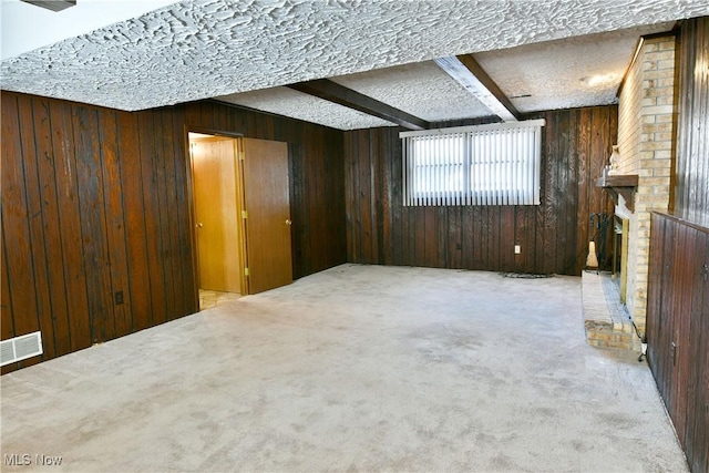 basement with a textured ceiling, carpet floors, a brick fireplace, and wood walls