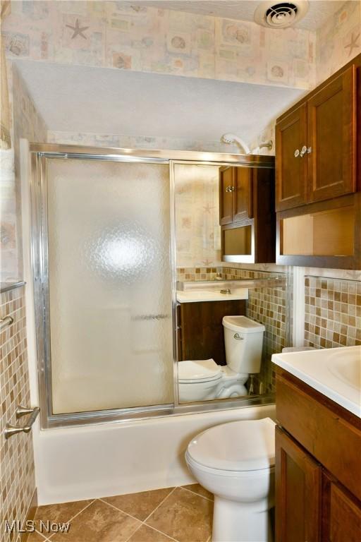 full bathroom featuring tile patterned floors, vanity, enclosed tub / shower combo, and tile walls