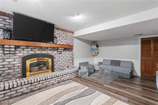 living room with hardwood / wood-style floors, a textured ceiling, and a brick fireplace