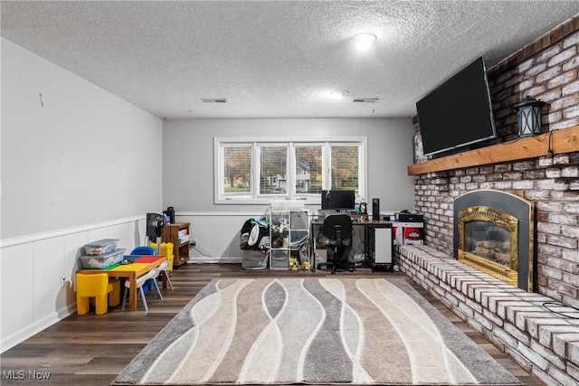 office area featuring a textured ceiling, a fireplace, and dark wood-type flooring