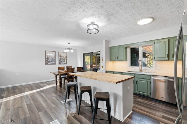 kitchen with stainless steel appliances, green cabinets, butcher block counters, and sink