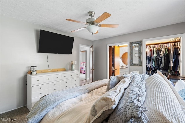 carpeted bedroom featuring a textured ceiling, connected bathroom, a closet, and ceiling fan