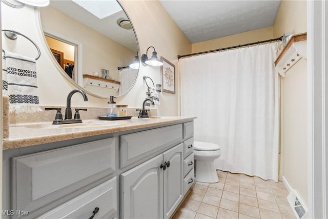 bathroom featuring a skylight, tile patterned flooring, a textured ceiling, toilet, and vanity