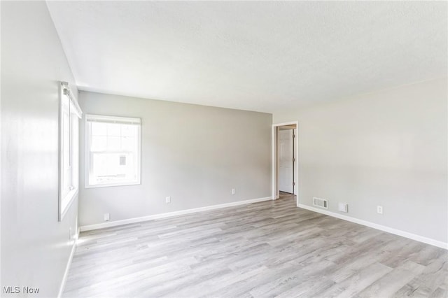 unfurnished room featuring light hardwood / wood-style floors and a textured ceiling