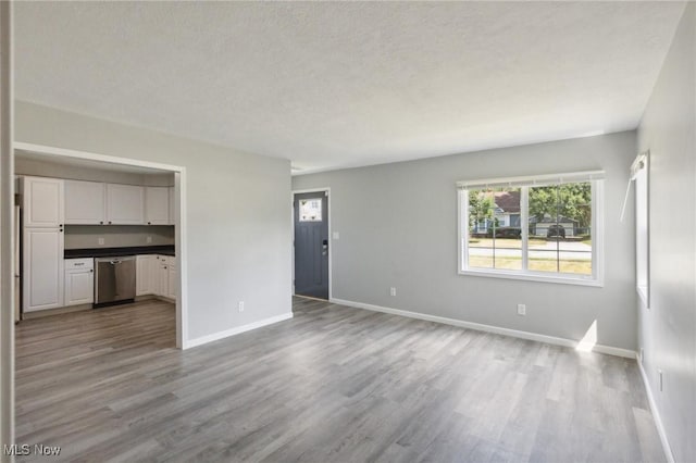 unfurnished living room with light hardwood / wood-style flooring and a textured ceiling