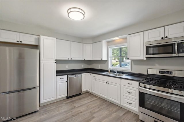 kitchen with stainless steel appliances, white cabinetry, light hardwood / wood-style floors, and sink