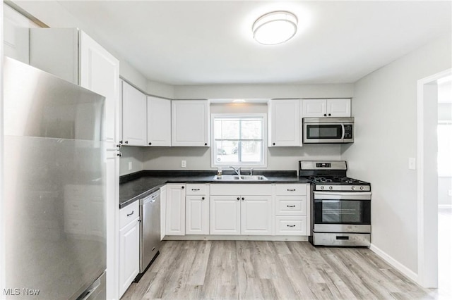 kitchen with sink, white cabinets, stainless steel appliances, and light wood-type flooring