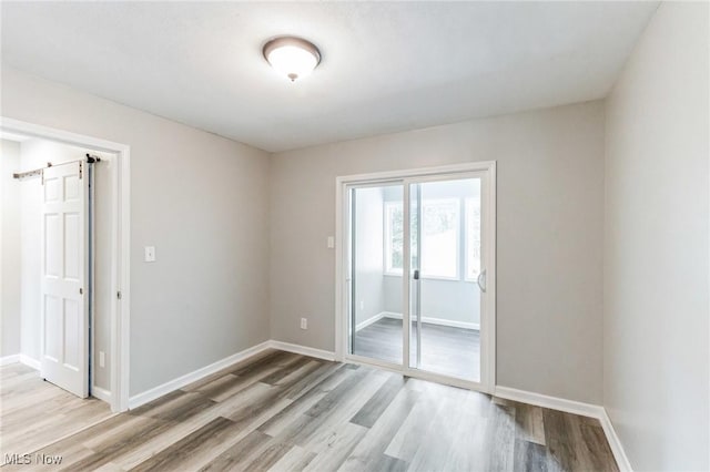 empty room with a barn door and light wood-type flooring