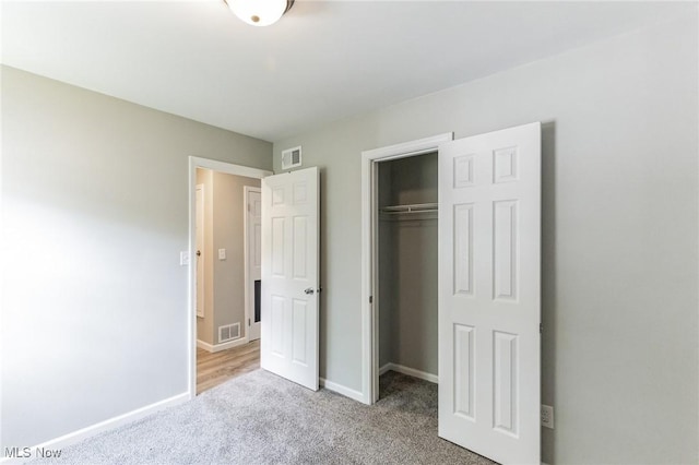 unfurnished bedroom with light carpet and a closet