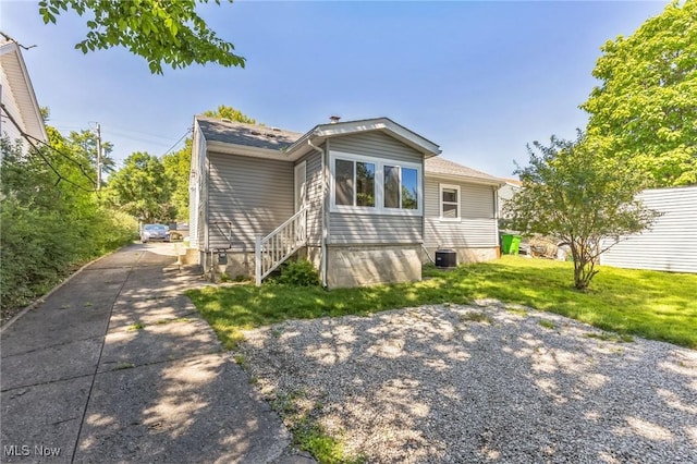 bungalow featuring a front lawn and central air condition unit