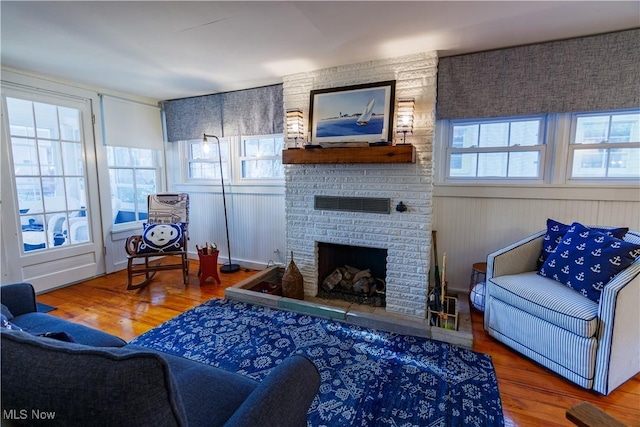 living room with wood-type flooring and a brick fireplace