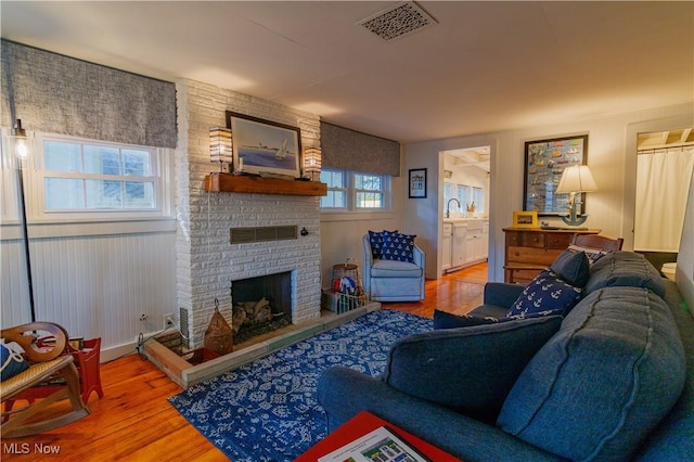 living room with hardwood / wood-style flooring and a brick fireplace