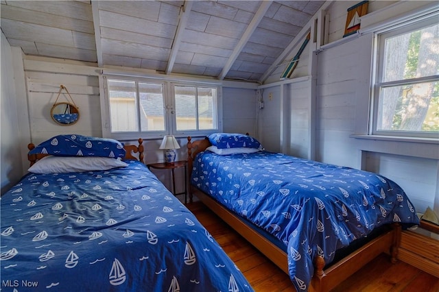 bedroom with hardwood / wood-style flooring, multiple windows, lofted ceiling, and wood walls